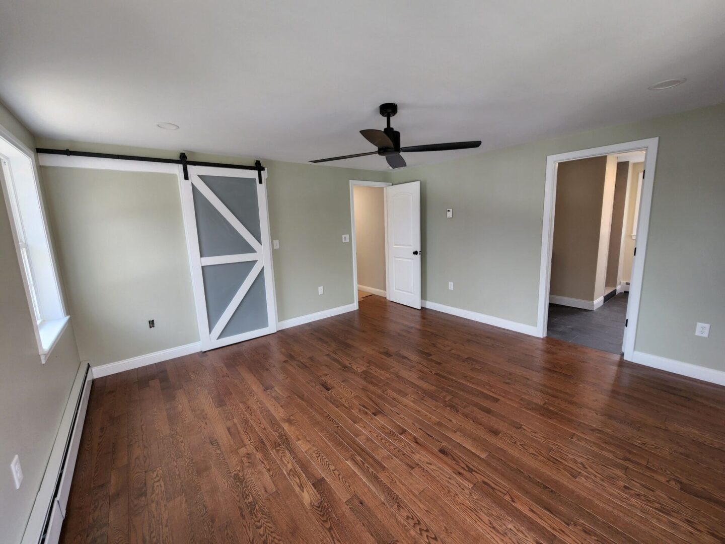 A room with wood floors and a barn door.